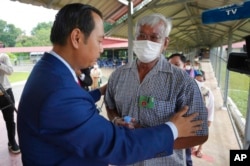 Sum Rithy, right, former Khmer Rouge survivor, cries as he is helped by a court spokesman into the courtroom before the hearings against Khieu Samphan, in Phnom Penh, Cambodia, Sept. 22, 2022.