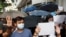 FILE - Supporters raise white paper to avoid slogans banned under the national security law as they support arrested anti-law protester outside Eastern court in Hong Kong, July 3, 2020.