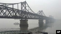 FILE - Trucks move across the bridge linking North Korea with the Chinese border city of Dandong, March 3, 2016. China in April banned imports of gold and rare earths from North Korea, as well as fuel jet exports. 