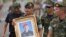 An honor guard hold up a picture of Samarn Poonan, 38, a former member of Thailand's elite navy SEAL unit who died working to save 12 boys and their soccer coach trapped inside a flooded cave as family members weep at a airport, in Rayong province, Thailand, July 6, 2018.