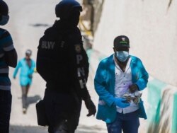 A forensic investigator carries a bagful of bullet casings collected at the residence of Haiti's President Jovenel Moise, where he was killed by gunmen in the early morning hours, in Port-au-Prince, Haiti, July 7, 2021.