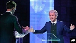 Right-wing populist leader Geert Wilders gestures as he talks to Dutch Prime Minister Mark Rutte, left, during a national televised debate, the first head-to-head meeting of the two political party leaders since the start of the election campaign, at Erasmus University in Rotterdam, Netherlands, March 13, 2017.