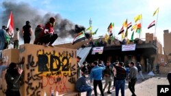 Pro-Iranian militiamen and their supporters set a fire during a sit-in in front of the U.S. embassy in Baghdad, Iraq, Wednesday, Jan. 1, 2020.