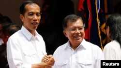 Indonesian presidential candidate Joko "Jokowi" Widodo (L) and his vice presidential running mate Yusuf Kalla shake hands during an event declaring their bid in the upcoming July 9 election, in Jakarta, May 19, 2014.
