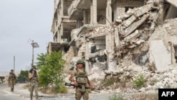 Turkish soldiers patrol along a road past destroyed buildings atop the Arbaeen hill overlooking Ariha in the southern countryside of Syria's Idlib province on May 26, 2020.