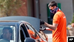 Randy Barnes, a restaurant worker who has been laid off due to the coronavirus pandemic, loads food for a customer at a drive thru operated by Carrboro United in Carrboro, N.C., March 26, 2020.