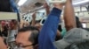 Para penumpang, sebagian besar mengenakan masker, tampak berdesakan di dalam kereta di Jakarta, hari Senin (23/3) di tengah perebakan virus corona.