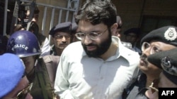 Polisi Pakistan mengawal Ahmed Omar Saeed Sheikh, yang didakwa membunuh wartawan AS, Daniel Pearl, pada 2002, keluar dari gedung pengadilan di Karachi, Pakistan, 29 Maret 2002.