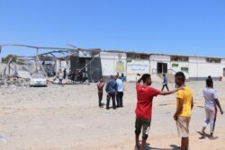 After the bombing of the detention center that killed more than 50 civilians and wounded more than 130, migrants watch authorities search for human remains, near Tripoli, Libya, July 3, 2019. (H. Murdock/VOA)