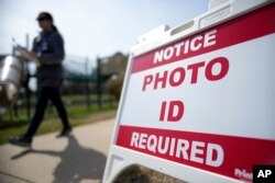 FILE - A Super Tuesday voter walks past a sign requiring photo identification at a polling location in Mount Holly, North Carolina, March 5, 2024.
