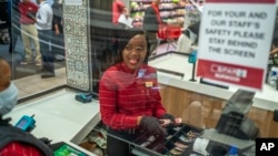 Zandile Mlotshwa, 21 ans, caissière au supermarché Spar dans la banlieue de Norwood à Johannesburg, compte son argent à la fin de sa journée de travail le 30 mars 2020. (AP Photo/Jerome Delay)