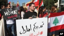 Activists hold Lebanese flags and an Arabic placard, center, that reads: "your extension is an occupation, no to the extension," during a protest against the extension of the Lebanese parliament, on a road that leads to the Parliament building, in downtown Beirut, Nov. 5, 2014.