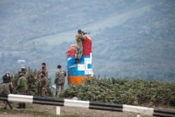 A sniper of Nagorno-Karabakh's militia observes the land ahead during a military conflict near Hadrut, the separatist region of Nagorno-Karabakh, Oct. 11, 2020.
