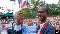 Alpha Saliou Diallo, a refugee from Guinea, holds his daughter, Aisha, after he became a U.S. citizen during a special naturalization ceremony commemorating World Refugee Day at the Delacorte Theater in New York City's Central Park, June 20, 2016.