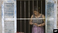 In this photo, taken on Mar. 17, 2011, a woman stands by a window of her house on the edge of Boeung Kak, Phnom Penh's largest lake. She and other residents of the area are being evicted from their homes to make way for upscale villas and office building