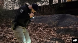 A New York City police officer searches for evidence related to the killing of UnitedHealthcare CEO Brian Thompson, in Central Park in New York, Dec. 6, 2024.