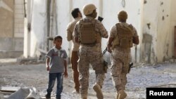 Seorang pria berjalan melewati tentara koalisi yang dipimpin Saudi di Aden, Yaman, 26 September 2015 (Foto: dok). 