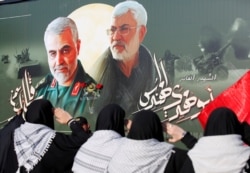 FILE - Iraqi women gather at the scene where Iran's Quds Force top commander Qassem Soleimani and Iraqi militia commander Abu Mahdi al-Muhandis were killed in a U.S. airstrike at Baghdad airport, Iraq, Feb. 13, 2020.