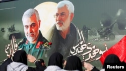 FILE - Iraqi women gather at the scene where Iran's Quds Force top commander Qassem Soleimani and Iraqi militia commander Abu Mahdi al-Muhandis were killed in a U.S. airstrike at Baghdad airport, Iraq, February 13, 2020.