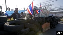 Anti-government protesters wave national flags as they block intersection during rally in Bangkok, Jan. 13, 2014.