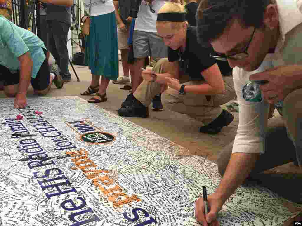 Mourners sign a banner outside the Emanuel AME Church in Charleston, June 19, 2015. (Amanda Scott/VOA)
