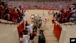 Corredores y toros llegan a la plaza de toros durante el octavo y último encierro de las fiestas de San Fermín en Pamplona, en el norte de España, el domingo 14 de julio de 2019.