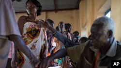 Voters wait in line to cast their vote, as others have their fingers dipped in ink to show they have done so, in an abandoned school used as a polling center in the disputed border region of Abyei, Oct. 27, 2013.