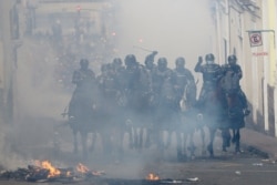 Mounted police cross a burning barricade in pursuit of anti-government demonstrators during a nationwide strike against President Lenin Moreno and his economic policies, in Quito, Ecuador, Oct. 9, 2019.