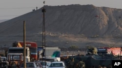 On the outskirts of Suruc at the Turkey-Syria border, Turkish forces patrol as militants with the Islamic State group place their group's flag on a hilltop at the eastern side of the town of Kobani, Syria.