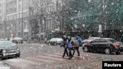 Young people cross a street amid a snow flurry in central Kyiv, Ukraine March 27, 2019. The country holds presidential elections Sunday.