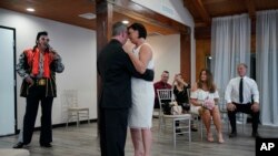 Charles King sings as Elvis as he marries Alicia Funk, center right, and Vaughan Chambers at A Little Wedding Chapel on May 12, 2020, in Las Vegas. (AP Photo/John Locher, File)