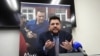 FILE - Leonid Volkov, chief of staff for Russian opposition leader Alexey Navalny (background photo), speaks during an interview at the European Parliament in Strasbourg, France, on Dec. 14, 2021. Kremlin critic Navalny was jailed in February 2021.