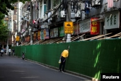 FILE - A man looks in through a gap in a barrier in a residential area, after the lockdown placed to curb the coronavirus disease (COVID-19) outbreak was lifted in Shanghai, China, June 7, 2022.