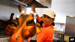 Artist Clary Salandy holds a giraffe head as she speaks with the Associated Press in her studio, ahead of the Platinum Jubilee Pageant, in London, June 1, 2022.