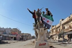 Turkey-backed Syrian fighters celebrate in the town of Saraqib in the eastern part of the Idlib province in northwestern Syria, Feb. 27, 2020.