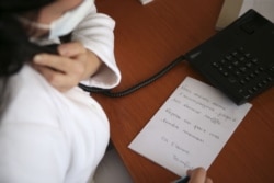 A nurse wearing a face mask writes down a telephone message from a deceased patient's family member, to be put in the victim's coffin, in Corsica, April 23, 2020.