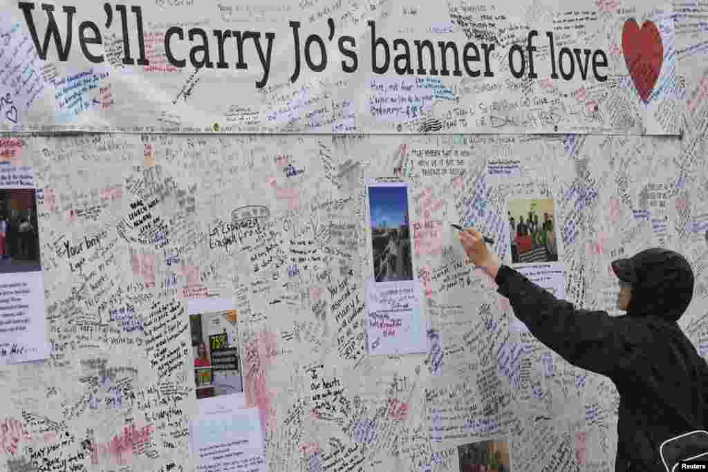 A man writes a tribute on a message board erected in memory of Labour Party MP Jo Cox, who was shot dead in Birstall, at Parliament Square in London, Britain.