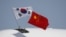 FILE - Flags from South Korea, left, and China flutter atop an aircraft at Beijing Capital International Airport in China, Sept. 2, 2015.