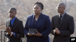 Isatu Salia carries the cremains of her husband, Ebola victim Dr. Martin Salia, while their sons Maada, 20, right, and Hinwaii, 12, walk with her to enter St. Mary's Church in Landover Hills, Md., for a funeral Mass, Nov. 29, 2014.
