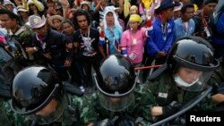 FILE - Soldiers hold their shields as officials leave a government office where Prime Minster Yingluck Shinawatra had been holding a meeting as anti-government protesters gather outside in Bangkok, Feb. 3, 2014.