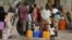 FILE - People gather at a tap in the Malkohi camp for internally displaced people as they collect water in Yola, Nigeria.