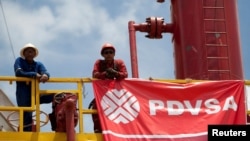 ARCHIVO - Trabajadores frente a una plataforma de perforación en un pozo petrolero operado por la petrolera estatal venezolana PDVSA, en Morichal. 