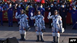 Astronauts Nie Haisheng (R), Liu Boming (C) and Tang Hongbo wave during a departure ceremony before boarding the Shenzhou-12 spacecraft before lift off on a Long March-2F carrier rocket at the Jiuquan Satellite Launch Centre in the Gobi desert in northwest China on June 17, 2021.