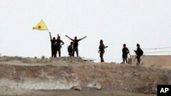Fighters with the Kurdish People's Protection Units, or YPG, wave their yellow triangular flag on the outskirts of Tal Abyad, Syria, June 15, 2015.
