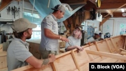 Apprentice program instructors Chris Cease, left, and Gabe Beckerman provide tips on building a sailboat to two of the apprentices. (Deborah Block/VOA)