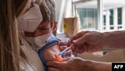 A mother holds her four year old son as he receives the child COVID-19 vaccine at Temple Beth Shalom in Needham, Massachusetts on June 21, 2022.