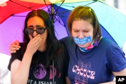 Abortion-rights activists react after hearing the Supreme Court decision on abortion outside the Supreme Court.