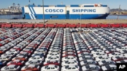 FILE - In this photo released by Xinhua News Agency, an aerial view shows manufactured vehicles before being loaded onto a cargo ship at the Yantai Port in eastern China's Shandong Province, Dec. 7, 2021.