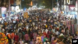 FILE - People crowd a market area outside a train station in Mumbai, India, March 12, 2022. 