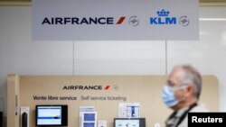 A passenger, wearing a protective face mask, walks past a self service ticketing of airline company Air France in the departures area at the Nantes-Atlantique airport in Bouguenais near Nantes, France, June 29, 2022. 